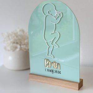 Personalizirana akrilna spominska ploščica ob rojstvu z 3D obrisom dojenčka, akrilnim imenom otroka in datumom rojstva na lesenem podstavku.